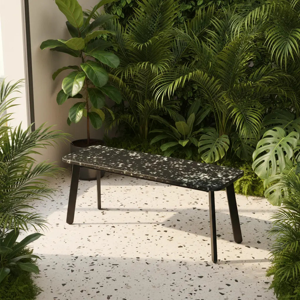 Black polymer bench made from recycled plastic panels, placed on a terrazzo terrace surrounded by lush tropical plants