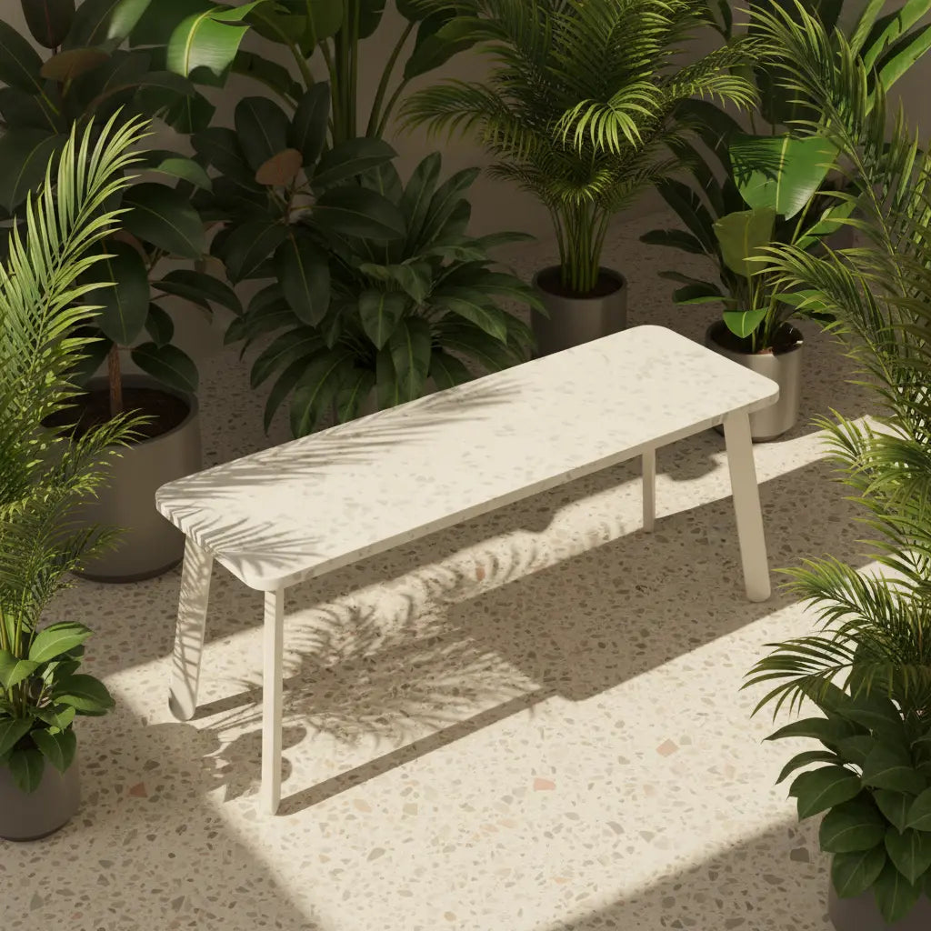 White recycled plastic bench on a sunlit terrazzo patio, surrounded by lush green plants, dappled shadows across the eco-friendly panel top